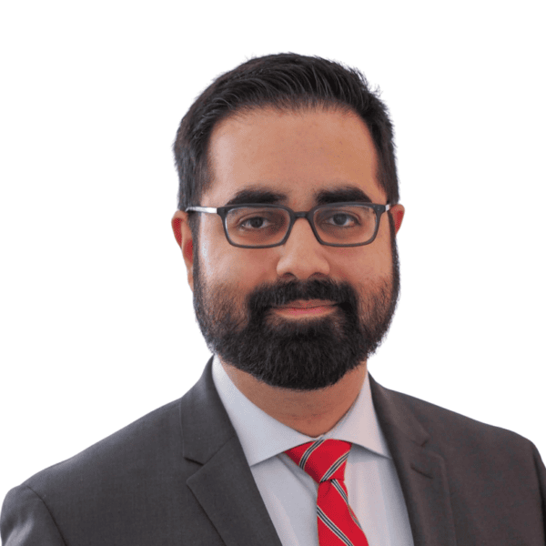 A man with dark hair and a beard, wearing glasses, a gray suit, a white shirt, and a red striped tie, smiles slightly against a white background.