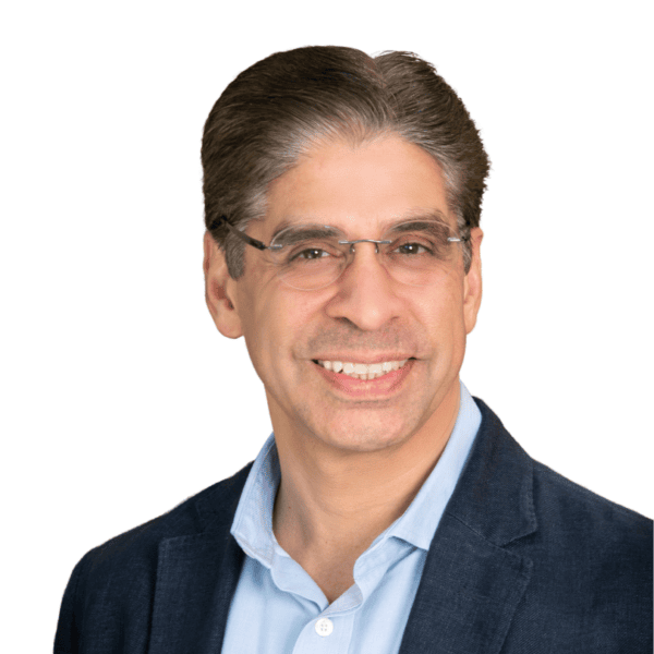 Smiling man with short brown hair, wearing glasses, a blue blazer, and a light blue collared shirt, against a white background.