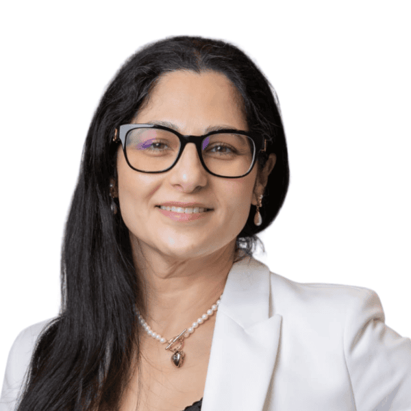 A woman with long dark hair, glasses, and a white blazer smiles at the camera. She is wearing a pearl necklace and earrings. The background is plain white.