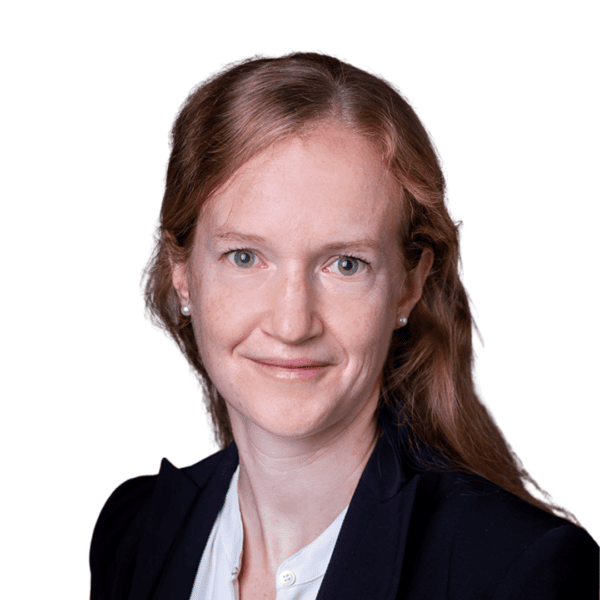 Professional woman with long reddish-brown hair, wearing a dark blazer and white blouse, smiling slightly, facing forward against a plain white background.
